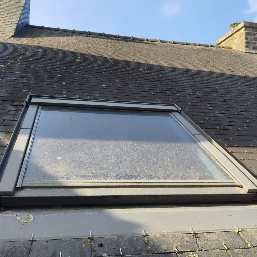 Velux en toiture avant nettoyage : le verre est mat, couvert d'un dépôt gris qui masque complètement le ciel